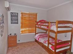 13 Andrews Court, Braitling, NT 0870 This five bedroom, two bathroom property is ready for a big family to move in and make it their own! Located on a corner block of a private court the property is completely fenced from the outside and it provides a nice private feel around the perimeter of it. The entry to the home is directly next to the huge carport/verandah. As you enter into the home the galley style kitchen is to your left and to the right is the dining room. This area is completely tiled too and is separate from the kitchen/dining area. The dining area has a split system air conditioner also. The long galley style kitchen features gas cooking, electric oven, dishwasher and a good sized double sink with a window that looks over the undercover area which is perfect to keep an eye on the kids playing. Off from the dining area is the 5th bedroom which could also be used as a study and this room features laminate timber flooring. The lounge room has split system air conditioning and also features laminate timber flooring. A sliding glass door at one end of the lounge room leads to the front yard. 