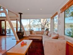 97 Richard Road Scotland Island | PMC Hill Real Estate Stylish and spacious this cedar waterfront home is filled with 
natural light and enjoys the tranquil surrounds of Pittwater while 
offering stunning views to Church Point and the Ku-ring-gai National 
Park. 
 Flexible in its two storey design the home features polished timber 
floors throughout and elevated 180 degree views to the National Park in 
the west. The home is located close to the main ferry wharf which 
provides easy access to Church Point which is only 3 minutes away. 
 The centrally located large modern kitchen incorporates a breakfast 
bar and dishwasher and flows effortlessly to the open plan lounge/dining
 room with a wide picture window and bifold doors which open to a full 
width balcony. A generously sized bedroom or home office, a third 
bedroom and a combined bathroom/laundry are also on this level. 
 The spacious master bedroom is located on the upper level with 
built-ins and sparkling water views through spotted gums. A full sized 
second bathroom and a cute A shaped child's bedroom with a loft cubby 
complete the upper level. 
 At the rear a large timber deck is ideal for entertaining and the 
grassed garden is perfect for children to play. The home has plenty of 
under house storage which, subject to approval, could be converted into 
more rooms if required. 
 Timber stairs and pathways lead through the fully landscaped front 
garden to the waterfront facilities which consist of a deep water jetty 
with a large entertaining landing and pontoon. 
 This home will impress families seeking space, comfort and lifestyle. 