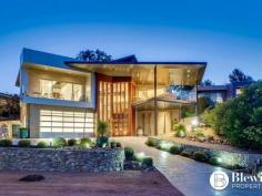  14 Aspen Rise Jerrabomberra NSW 2619 $1,450,000 Situated in the sought-after location of Aspen Rise is this striking and truly unique residence located in an elevated position opposite tranquil bushland and commanding glorious views. As you enter the grand foyer through the colossal custom pivoting front door you will be impressed by the two-storey feature stone wall with floating staircase, solid timber floors and a wrought iron gate which leads to the superb wine cellar. From the foyer you are guided up the stairs to the spectacular open plan living area. This space opens out to the entertaining area which overlooks bushland and provides views right through to the city. The open plan living area boasts solid timber floors, north facing windows including electric clerestory windows and glass doors that completely open up to create the ultimate inside outside living space. The living area consists of the kitchen, spacious lounge and dining areas which could easily cater for any sized furniture. The showstopper of the living area has to be the impressive kitchen with two stone and timber island benches that provide more bench space than you could wish for as well as an integrated fridge-freezer and new double ovens. The stunning master bedroom which is located at the front of the property also boasts outstanding views. This luxurious room offers its own large covered balcony, display shelves, double built-in robes as well as a one of a kind ensuite with stone bench top, timber feature wall and stone bulkhead that runs through to the bedroom. The remaining bedrooms all have built-in robes and views along with built-in sensor lit shelving. The main bathroom boasts a bath, large shower and feature stone vanity. The large laundry features the same stone bench, offers great storage and outdoor access. Outside you will find the second outdoor entertaining area with heated spa. This space includes a combination of open and covered spaces providing you with year-round entertaining options. As you wander up the yard you will find the viewing deck which leads on to the secluded fire pit area, vegetable gardens and storage shed. The designer landscaped gardens boast an extensive lighting plan and automated irrigation system programable from your phone and supplied by two 10,500 litre rain water tanks. The oversized double garage includes an impressive home office and workshop area. The garage offers hot and cold running water along with incredible storage solutions. For additional parking requirements there is a large carport located next to the front entrance. Ensure you make the time to view this remarkable masterpiece for yourself. Features: – Architecturally designed – Prestige location overlooking bush reserve – Magnificent views – Spectacular entry with floating staircase – Open plan living area – Solid timber floors – Custom kitchen cabinetry including integrated fridge-freezer – Two stone island kitchen benches – Back-lit wine cellar – Multiple outdoor entertaining areas – Elevated viewing platform and fire pit area – Raised vegetable gardens – Built-in natural gas BBQ – Bespoke stone features, doors and lighting – Solar panels – Ducted vacuum system – Ducted reverse cycle airconditioning – Security system with cameras – 2 car garage plus office and workshop space – Large carport next to front entry – Irrigated gardens, programmable by phone – 2 x 10,500 litre grey water and garden irrigation tanks PROPERTY FEATURES • 	 House • 	 4 bed • 	 2 bath • 	 3 Parking Spaces • 	 Alarm System • 	 Land is 1,021 m² • 	 3 Garage • 	 Remote Garage • 	 Dishwasher • 	 Built In Robes • 	 Vacuum System • 	 Balcony • 	 Deck • 	 Outdoor Entertaining .        Shed.. 
