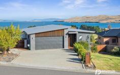  14 Estramina Drive Oakdowns Tas 7019 $835,000 This elegant and contemporary home overlooking Oakdowns showcases impressive water views and provides modern conveniences at every turn. Encompassing style and with no detail missed the home provides a matchless indoor/outdoor flow, finished off with sophisticated matte black fixtures and fittings, exposed timber, and frosted glass. The open-plan living, dining and kitchen space extend to a sun-soaked timber deck, with glass balustrades allowing for an uninterrupted picturesque vista. The spacious kitchen offers designer lighting illuminating the abundance of bench space. The area here provides elite appliances which are encased by sleek black cabinetry and custom timber shelving, including enviable wine storage. Comfort is assured with a wall-mounted reverse cycle heat pump. Awake to unrivalled views from the master bedroom with direct access to the rear deck. The en-suite has been designed with couples in mind with a duel walk-in shower, double sink vanity, and a coveted walk-in dressing room. The two remaining bedrooms, which can be separated from the main living areas, contain built-in wardrobes and offer endless sunshine. They are serviced by the chic family bathroom with walk-in glass shower, deep tub, toilet, and vanity. An entertainer’s and child’s dream, the fully fenced and low-maintenance grounds offer multiple options for gatherings and fully enclosed playground. The large balcony provides the best vantage point to enjoy the view, and a central, raised timber deck in the yard offers an additional spot to entertain. The double garage is secured by roller doors and can be accessed both externally and internally with additional off-street parking within the driveway. The garage also provides access to the yard and contains space for the laundry. Currently the garage is set up as a single garage with additional storage so that the current owners could include a fourth bedroom or home office. With no expense spared and the potential to increase living sizes with plans in place this is an, on-trend family home, in a superior location within a booming Eastern Shore community. It enjoys contemporary convenience coupled with the peace and quiet of a suburban setting. 