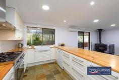  895 Kintore Rd Parkerville WA 6081 Multigenerational and packed to the rafters with family-focussed features, this Parkerville property has been at the heart of an extended family’s life for twenty-three years. Surrounded by 4.7 acres of pasture and bush, the property offers the perfect blend of a family home, a country property and bush living. 4 bedrooms 2 bathrooms 1975-built brick and tile 1 bedroom 1 bath flat UMR Renovated baths & laundry Open-plan kitchen/meals Huge undercover patio Studio + garage + workshop Scheme + tank + bore water 4.7-acres w auto entry gate Multi-generation family haven A pair of imposing front doors open to reveal the soft honey-tones of slate floors and a large, bright foyer. French doors lead to a lounge with timber-look floors, a slow-burning fire, and glazed doors to the front verandah and alfresco entertaining area. Glazing on four sides ensures this room is awash with natural light and filled with views of the surrounding landscape. A home office currently sits off the foyer. This generously proportioned room is fitted with a wardrobe recess, allowing new residents to style it as an additional bedroom; with the main bedroom nearby, it would make an ideal nursery or bedroom for a young child. The main bedroom sits at the front of the plan and boasts storage along two walls, a pair of retro arched windows and reverse cycle air conditioning. A fully tiled floor to ceiling renovated bathroom with pebble feature tiles, a shower, and a vanity brings modern style to the restful and welcoming parents’ retreat. From the foyer, slate tiles continue along a small hall to a walk-in pantry with full-height shelving and cupboards along each wall, providing ample storage for ingredients, appliances, cookbooks and tableware. It sits opposite a galley-style kitchen with timeless white cabinetry, a butler sink, and a timber benchtop with an integrated breakfast bar. A 900 mm Blanco oven brings an industrial edge to the gently country-style kitchen, and a dishwasher and plenty of storage ensure this is a practical workspace with solid family-friendly credentials. The integrated breakfast bar links the kitchen to a lounge/dining area with dual-aspect glazing and flowing movement to the alfresco entertaining area, blurring the distinction between indoor and outdoor living and entertaining. Reverse cycle air conditioning and a slow-combustion fire confirm this room as the year-round heart of the home. Underpinning an impeccable indoor-outdoor layout is the huge paved alfresco entertaining area under a gable roof. This garden-edged area provides ample space for extended family to come together for impromptu meals or festive celebrations and offers a natural meeting point between the principal residence and the self-contained Granny/Aunty/Teenager’s flat. A long verandah extends across the rear of the home with steps leading to a terrace and expanse of lawn. A fenced area has been used to contain a spa and above-ground pool and could do so again. Two junior bedrooms with reverse cycle air conditioning, open shelving, and wardrobes feature timber floors and a neutral colour palette. They are large enough to accommodate a king-size bed. The junior bedrooms share a fully tiled, renovated family bathroom and a separate WC. Completing the layout in the junior wing is a walk-through laundry with a door to the spacious flat set under the main roof. The internal door linking the home and flat opens into a dining room with a kitchen on one side. Timber look floors extend across the flat. A family room with a slow-combustion fireplace and reverse cycle air conditioning benefits from views of the garden and large windows on two sides. With its own front door, residents of the flat enjoy an independent lifestyle while retaining a connection to the family in the principal residence. The main bedroom is filled with lush garden views and features a walk-in robe and storage cupboard along with the modern ensuite with shower vanity and WC. Surrounded by 4.7 acres of pasture and bush, the property boasts numerous outbuildings, including an air-conditioned two-room studio suited to myriad uses, a two-car garage with power and a powered 10m x 10.5m workshop with a small mezzanine storage area and double doors for in-out access. Numerous nut trees, small orchard, raised beds which provide space for growing vegetables, and a chicken coop provides shelter for feathered friends. A single paddock is home to the current owners’ goats. Whatever the shape of your family and your vision of the life you create together, this impressive property has what it takes to bring that vision to life. Local schools, the bustling village of Mundaring, sports and outdoor activities, and transport links are all within easy reach. 