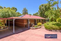  9 Clipson Cres Mundaring WA 6073 $899,000 Hidden behind a lush, vibrant front garden, this home is a true sanctuary in the serene, glen-like setting of the prestigious Noblewood Estate. From the moment you arrive, the home invites you in with its timeless charm and thoughtful design. With schools, parks, the bridle trail and Mundaring Village all within easy reach, it is perfect for families who value comfort, convenience, and a connection to nature. 4 bedrooms 2 bathrooms 2000-built brick and iron Central open-plan living Indoor-outdoor floorplan Elevated alfresco entertain RC air con & ceiling fans Drive-in gated rear access Tandem carport storeroom Landscaped 2001 sqm lot Walk to school and park Designed to celebrate light, space, and the inimitable beauty of the Perth Hills, this delightful home offers a wide south-facing verandah, a perfect perch to watch birds flit and play in the front garden, and a deep, sheltered patio, an elevated site for relaxing and entertaining against a backdrop of majestic gums standing sentinel at the property’s rear boundary. Large windows across the rear of the home invite a beautiful quality of natural light into the interior spaces. To one side of the tiled entrance, a well-considered layout unfolds, featuring a convenient guest powder room, a cozy minor bedroom, and the principal suite, providing a peaceful retreat with plenty of space for relaxation. At the heart of the home lies the open-plan kitchen, meals area, and family room, a bright and inviting space designed to bring loved ones together. Natural light floods the area, accentuating its spaciousness and warmth. Every season is a delight, with reverse-cycle air and a ceiling fan. One corner of this open plan features a kitchen equipped for culinary creations. Anchored by a stone-topped bench and integrated breakfast bar, it is a cook’s delight. A walk-in pantry and cabinetry in a soft cream finish provide ample storage and ensure everything has its place. Meal prep is a breeze, thanks to an electric oven, gas hob, and dishwasher that make clean-up effortless. Comfort, elegance, and considered design converge to create a haven for every family member. This property is tailored to meet the demands of modern living with an ideal balance of privacy and shared spaces. The principal bedroom is a blissful retreat at the rear of the plan. North-facing windows flood the space with filtered light, offering a serene start to each day with breathtaking views of the surrounding landscape. This sanctuary, humming with an air of comfort and calm, is complemented by a private ensuite and a spacious walk-in wardrobe. The design effortlessly accommodates family life with a junior wing that extends from the central living area – comprising two carpeted bedrooms with built-in robes, a well-appointed family bathroom, and a convenient walk-through laundry. The third junior bedroom is currently styled as a home office and would make an ideal guest room or nursery for a young child. A large walk-in linen press adds extra practicality, ensuring every corner of this home is as functional as stylish. Step out onto the north-facing verandah, where you’ll find an ideal spot to entertain, dine alfresco, or bask in the tranquil ambience of your private oasis. For those who love to entertain, the large paved and covered outdoor space offers an inviting area to gather with friends and family. Whether it’s a casual weekend barbecue or a more formal soirée, this elevated space, looking across gardens to a landscape dotted with eucalypts and grass trees, will make outdoor entertaining a joy, no matter the occasion. With every element referencing the stunning Hills setting – luminous interiors, seamless indoor-outdoor connections and relaxed style – this home is designed to elevate everyday living while maintaining a sense of connection and harmony. 