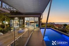 11 Mippi Rd Halls Head WA 6210 $2,400,000 Darren Ahearn and Emma Hutton are proud to present 11 Mippi Road, Halls Head-a premium Madison home, perched high in the sky and surrounded by breathtaking ocean views. This impressive four bedroom, four bathroom and a four car garage is set on an expansive 1,408 sqm elevated block. A stylish and secluded residence like this must be seen to be believed; but be warned, a visit will forever raise your expectations of what property can achieve. Step inside the exceptional indoor-outdoor living space, where a show stopping pool seamlessly blends with breathtaking ocean views. A stylish tiled seating area and lush greenery create a resort-like ambiance. Through the double glazed, double bi-fold doors, soaring ceilings and sleek porcelain tiling set the stage for luxurious living. The stunning kitchen and scullery feature premium engineered stone benchtops, a waterfall-edge island with a built-in mini fridge, and a five burner top gas cooktop, all with ocean views. Both the living and dining areas open onto the expansive balcony, offering uninterrupted coastal vistas. As you walk down the extra width hallway, glass plantation louvers let in natural light and offer a clear view of the stunning pool and established easy-care tropical garden. The master bedroom boasts a spacious hallway and an open ensuite design featuring a double floating basin, full width vanity with LED mirror lighting. This stunning room benefits from exceptional design prowess; the orientation offers both sanctuary and stunning views of the outdoor area, pool and ocean. Guests or residences to the rest of the home will also feel like they are on holiday, with two of the three family bedrooms complemented by their own modern ensuites and one enjoying convenient access to the main stylish bathroom. Furthermore, two of the bedrooms offer stunning ocean views. The ensuites are sleek and contemporary, each featuring a shower and toilet. The main bathroom is beautifully designed with a bath, shower, and striking grey tiling throughout. The expansive four-car garage is a car enthusiast’s dream and is fitted with durable two pack flooring, dual high roof auto garage doors, plus a sauna for added luxury. In addition, the rear of the property contains an impressive double brick extra height powered workshop. This building has been designed with the potential to be a habitable residence in the future, with some further adaptation. This ancillary building has drive through access with an extra wide and extra width commercial roller door to allow access for all the toys. Features: – 1,408 sqm elevated block – Infinity style pool – Ocean views – Large powered workshop – Ducted reverse cycle air conditioner – 4 car garage with sauna – 4 bedrooms, 4 bathrooms – Under house storage – Double glazed windows This exceptional property has a unique bespoke design, with unprecedented views and high end finishings. This home exudes earthed ambiance with modern luxury flare. You must see this home in person to truly appreciate what is on offer here -without a doubt, a once-in-a-lifetime opportunity. Don’t miss your chance to make 11 Mippi Road Halls Head your new home. 