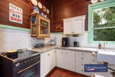  2965 Jacoby St Mundaring WA 6073 $1,000,000 In the heart of Mundaring, where the rhythm of modern life meets Western Australia’s pioneering past, stands a weatherboard and iron cottage that embodies the very essence of heritage living. Built circa 1901 by retired Bunbury harbour master Captain Thomas Scott, the remarkable “Stratheden” carries within its weatherboard walls the pioneering spirit that shaped early Western Australia. Hidden from the street by a charming picket fence and enveloped in lush, established gardens, this remarkable workers’ cottage offers a rare opportunity to inhabit a piece of living history whilst enjoying the unparalleled convenience of one of the region’s most coveted locations. 3 bedrooms 1 bathroom 1901 weatherboard & iron Striking workers’ cottage Extensive Jarrah panelling Wide jarrah floorboards High pressed metal ceilings Rear lane access to garage Estab gardens, bore retic 2023 sqm heart Mundaring Steps to Trail, park, village The extensive use of jarrah throughout this property immediately distinguishes it as a superior example of vernacular architecture, where wide floorboards and striking panelling speak to the craftsmanship and material abundance of a bygone era. Here, the integrity of the original fabric has been meticulously preserved, creating an authentic connection to the past that is increasingly rare. This is not simply a house that has been renovated; it is a heritage treasure that has been lovingly maintained, telling the story of Western Australia’s timber heritage. The approach to the home sets the tone for what lies beyond – a wide, bullnose verandah extends a gracious welcome, while pressed glass in subtle pastel hues surrounds the front door like jewels set within a frame. Living here means beginning each day with this gentle beauty, where morning light filters through coloured glass and the established gardens create a private sanctuary mere steps from Mundaring’s vibrant village centre. Upon crossing the threshold, the significance and integrity of this property become immediately apparent through the soaring ceiling, its pressed metal painted white, creating a striking vertical dimension that speaks to the generous proportions seen throughout the home. Picture rails and wide jarrah floorboards create a striking welcome that sets expectations high, and the home delivers on every promise. The entrance hall is flanked by two generously proportioned bedrooms, each graced with original windows, pressed metal ceilings and decorative fireplaces. At the end of the hallway, a pair of interior doors open to reveal the property’s masterpiece – a living room that embodies an authentic and uniquely Western Australian aesthetic. Vertical jarrah boarding rises to dado height, and horizontal panelling continues to the jarrah-clad ceiling. An expanse of eight-paned windows draws northern light into the heart of the home, creating a space where the seasons become part of daily life, where winter afternoons glow golden against the jewel-toned timber and summer mornings arrive soft and bright. Living in this room means inhabiting a space where craftsmanship and comfort converge, where every surface speaks to the skill of builders who understood both beauty and function. At one corner of this magnificent living space, a breakfast nook provides an intimate setting for morning rituals, whilst the kitchen represents a faultless melding of history and modern convenience. The original chimney breast and hearth, fitted with a Metters stove, anchor the space with authentic period detail, while pressed metal and jarrah panelling blend seamlessly with gold-flecked stone benchtops, under-bench cabinets, and contemporary appliances, including a freestanding electric oven and dishwasher. This kitchen exemplifies how heritage properties can incorporate modern elements without compromising their character. The principal bedroom, accessed via the living room, offers generous proportions. High ceilings ensure an airy, relaxed atmosphere that transforms sleep into restoration, whilst a separate walk-in robe and dressing room provide practical luxury. Reverse cycle air conditioning delivers year-round comfort, demonstrating that while heritage is honoured, contemporary expectations for comfort are uncompromised. Spanning the rear of the plan, a sunroom with a swathe of windows looking out to the rear garden creates a seamless connection between indoor and outdoor living. Terracotta floor tiles ground the space in earthy authenticity, while reverse-cycle air conditioning and direct access to both the rear garden and an alfresco entertaining zone ensure this bright space suits year-round use. A family bathroom and well-appointed laundry at either end of the sunroom complete the thoughtful arrangement of spaces. The transition to outdoor living occurs through French doors that connect the sunroom to a large, crazy-paved patio set beneath a wisteria-threaded pergola – a space where entertaining becomes effortless and where the changing seasons provide an ever-evolving backdrop. Living here means experiencing the joy of alfresco dining where privacy and tranquillity coexist with incredible accessibility to village amenities. The current owner’s dedication as a skilled and passionate gardener has created botanical magic that transforms this property from merely impressive to utterly enchanting.  Bore reticulated lawns and gardens cocoon the outdoor living spaces, creating profound privacy and calm despite the home’s remarkably central location. Camellia, deciduous trees, and hardy native plants create a tapestry of colour, texture, and seasonal interest that rewards close observation and daily enjoyment. Practical considerations have not been overlooked – rear lane access leads to a powered garage and a remarkable railway carriage studio, a two-room space complete with verandah that offers endless possibilities for creative pursuits, home business ventures, or simply a peaceful retreat. A small garden shed and single carport enhance the home’s practical amenities. The location represents perhaps the property’s greatest triumph – positioned mere steps from the Sculpture Park and Heritage Trail, with the shops and services of Mundaring Village within comfortable walking distance. Schools, sporting facilities, and public transport networks are all within easy reach of this hidden oasis, creating a lifestyle where convenience never requires compromise of character or tranquillity. Living here means enjoying the best of both worlds: the peace of established gardens and heritage architecture, paired with the vibrancy and accessibility of one of the Hills’ most desirable communities. True luxury lies in authenticity, craftsmanship and connection to place. Here, in this superior example of vernacular architecture, surrounded by a mature garden landscape and positioned in Mundaring’s coveted heart, the past and present converge to create something genuinely extraordinary. 