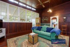  2965 Jacoby St Mundaring WA 6073 $1,000,000 In the heart of Mundaring, where the rhythm of modern life meets Western Australia’s pioneering past, stands a weatherboard and iron cottage that embodies the very essence of heritage living. Built circa 1901 by retired Bunbury harbour master Captain Thomas Scott, the remarkable “Stratheden” carries within its weatherboard walls the pioneering spirit that shaped early Western Australia. Hidden from the street by a charming picket fence and enveloped in lush, established gardens, this remarkable workers’ cottage offers a rare opportunity to inhabit a piece of living history whilst enjoying the unparalleled convenience of one of the region’s most coveted locations. 3 bedrooms 1 bathroom 1901 weatherboard & iron Striking workers’ cottage Extensive Jarrah panelling Wide jarrah floorboards High pressed metal ceilings Rear lane access to garage Estab gardens, bore retic 2023 sqm heart Mundaring Steps to Trail, park, village The extensive use of jarrah throughout this property immediately distinguishes it as a superior example of vernacular architecture, where wide floorboards and striking panelling speak to the craftsmanship and material abundance of a bygone era. Here, the integrity of the original fabric has been meticulously preserved, creating an authentic connection to the past that is increasingly rare. This is not simply a house that has been renovated; it is a heritage treasure that has been lovingly maintained, telling the story of Western Australia’s timber heritage. The approach to the home sets the tone for what lies beyond – a wide, bullnose verandah extends a gracious welcome, while pressed glass in subtle pastel hues surrounds the front door like jewels set within a frame. Living here means beginning each day with this gentle beauty, where morning light filters through coloured glass and the established gardens create a private sanctuary mere steps from Mundaring’s vibrant village centre. Upon crossing the threshold, the significance and integrity of this property become immediately apparent through the soaring ceiling, its pressed metal painted white, creating a striking vertical dimension that speaks to the generous proportions seen throughout the home. Picture rails and wide jarrah floorboards create a striking welcome that sets expectations high, and the home delivers on every promise. The entrance hall is flanked by two generously proportioned bedrooms, each graced with original windows, pressed metal ceilings and decorative fireplaces. At the end of the hallway, a pair of interior doors open to reveal the property’s masterpiece – a living room that embodies an authentic and uniquely Western Australian aesthetic. Vertical jarrah boarding rises to dado height, and horizontal panelling continues to the jarrah-clad ceiling. An expanse of eight-paned windows draws northern light into the heart of the home, creating a space where the seasons become part of daily life, where winter afternoons glow golden against the jewel-toned timber and summer mornings arrive soft and bright. Living in this room means inhabiting a space where craftsmanship and comfort converge, where every surface speaks to the skill of builders who understood both beauty and function. At one corner of this magnificent living space, a breakfast nook provides an intimate setting for morning rituals, whilst the kitchen represents a faultless melding of history and modern convenience. The original chimney breast and hearth, fitted with a Metters stove, anchor the space with authentic period detail, while pressed metal and jarrah panelling blend seamlessly with gold-flecked stone benchtops, under-bench cabinets, and contemporary appliances, including a freestanding electric oven and dishwasher. This kitchen exemplifies how heritage properties can incorporate modern elements without compromising their character. The principal bedroom, accessed via the living room, offers generous proportions. High ceilings ensure an airy, relaxed atmosphere that transforms sleep into restoration, whilst a separate walk-in robe and dressing room provide practical luxury. Reverse cycle air conditioning delivers year-round comfort, demonstrating that while heritage is honoured, contemporary expectations for comfort are uncompromised. Spanning the rear of the plan, a sunroom with a swathe of windows looking out to the rear garden creates a seamless connection between indoor and outdoor living. Terracotta floor tiles ground the space in earthy authenticity, while reverse-cycle air conditioning and direct access to both the rear garden and an alfresco entertaining zone ensure this bright space suits year-round use. A family bathroom and well-appointed laundry at either end of the sunroom complete the thoughtful arrangement of spaces. The transition to outdoor living occurs through French doors that connect the sunroom to a large, crazy-paved patio set beneath a wisteria-threaded pergola – a space where entertaining becomes effortless and where the changing seasons provide an ever-evolving backdrop. Living here means experiencing the joy of alfresco dining where privacy and tranquillity coexist with incredible accessibility to village amenities. The current owner’s dedication as a skilled and passionate gardener has created botanical magic that transforms this property from merely impressive to utterly enchanting.  Bore reticulated lawns and gardens cocoon the outdoor living spaces, creating profound privacy and calm despite the home’s remarkably central location. Camellia, deciduous trees, and hardy native plants create a tapestry of colour, texture, and seasonal interest that rewards close observation and daily enjoyment. Practical considerations have not been overlooked – rear lane access leads to a powered garage and a remarkable railway carriage studio, a two-room space complete with verandah that offers endless possibilities for creative pursuits, home business ventures, or simply a peaceful retreat. A small garden shed and single carport enhance the home’s practical amenities. The location represents perhaps the property’s greatest triumph – positioned mere steps from the Sculpture Park and Heritage Trail, with the shops and services of Mundaring Village within comfortable walking distance. Schools, sporting facilities, and public transport networks are all within easy reach of this hidden oasis, creating a lifestyle where convenience never requires compromise of character or tranquillity. Living here means enjoying the best of both worlds: the peace of established gardens and heritage architecture, paired with the vibrancy and accessibility of one of the Hills’ most desirable communities. True luxury lies in authenticity, craftsmanship and connection to place. Here, in this superior example of vernacular architecture, surrounded by a mature garden landscape and positioned in Mundaring’s coveted heart, the past and present converge to create something genuinely extraordinary. 